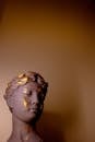 A Gold and Gray Woman Bust Sculpture Beside Brown Wall