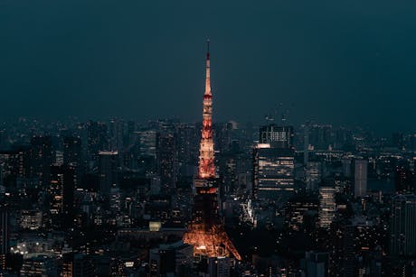 Stunning view of Tokyo Tower lit up at night, surrounded by the urban skyline of Minato City, Tokyo.