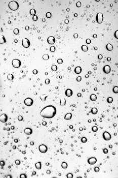 High contrast image of water droplets on a glass surface, showcasing purity and freshness.
