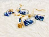 From above of identical small decorative bottles with blue evil eyes and round bungs with threads on soft plaid