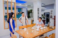 Serious Asian man with laptop interacting with friends at home