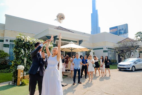 Content bride with groom throwing flower bouquet to guests outdoors