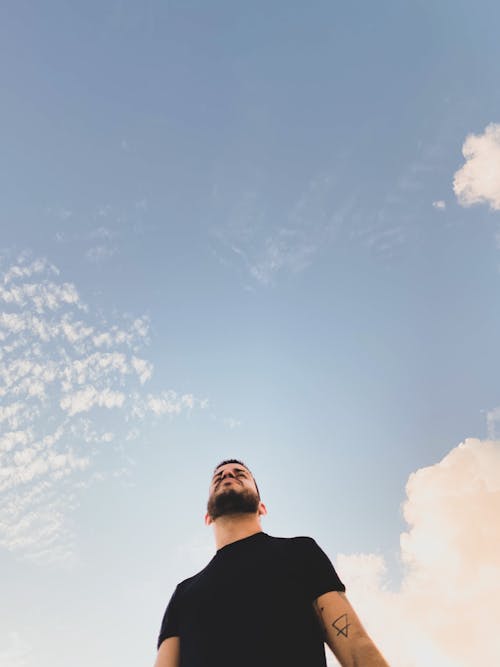 Stylish ethnic hipster man under cloudy sky