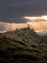 Person Standing on Rocky Hill during Sunset