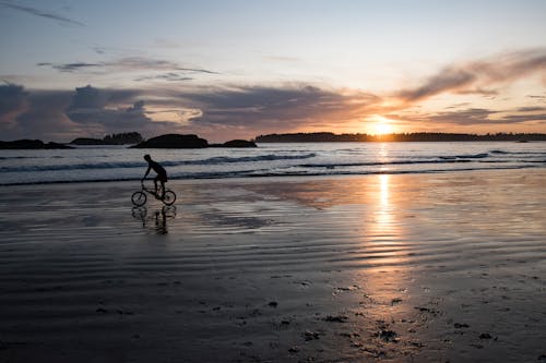Silhouette of Person Riding a Bicycle on Beach during Sunset
