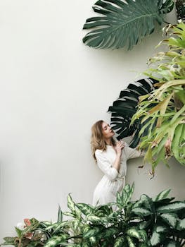 Woman in White Long Sleeve Dress Standing Beside Green Plants with Big Leaves with the Quote "Many men go fishing all of their lives without knowing that it is not fish they are after." written on it and have average color value #A7AD9D