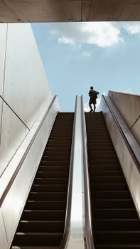 在奥地利维也纳蔚蓝的天空下，一个人站在自动扶梯上
