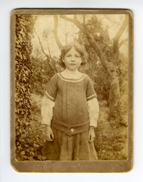 Old Photo of Girl Standing Near Trees and Plants