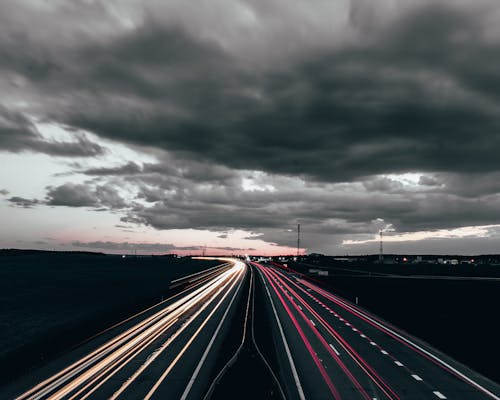Time Lapse Photography of Cars on Road Under Dark Clouds