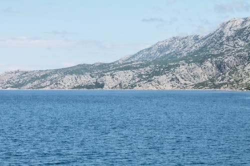 Free Rough mountain near ocean under cloudy sky Stock Photo