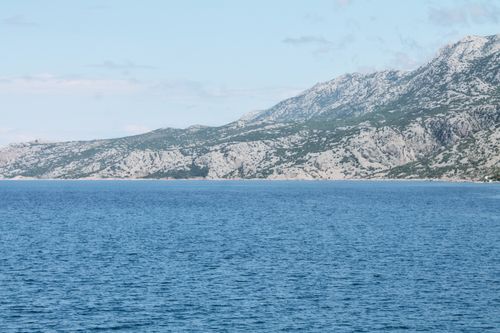 Free Scenery view of bristly ridge near sea with rippled water under blue cloudy sky in daytime Stock Photo