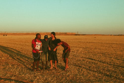 Group of Happy Men Standing on Brown Field