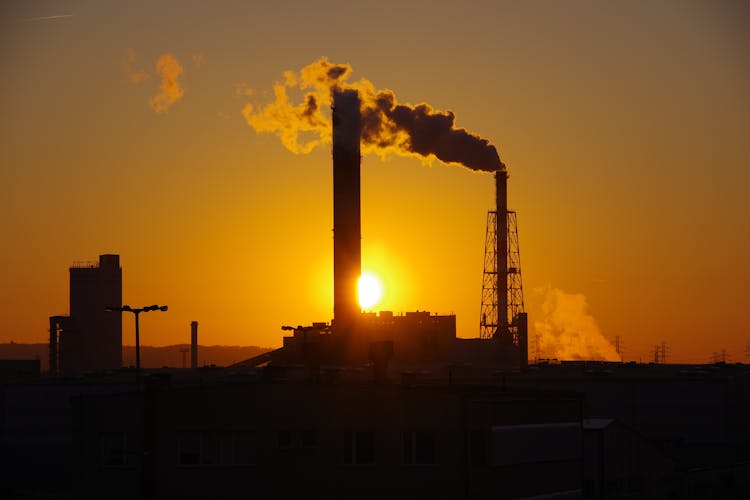 Smokestack With Vapor Cloud Under Bright Sky At Sunset