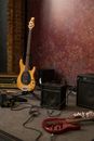 Stage in rehearsal studio with modern electric guitars and stereo acoustic system against red wall