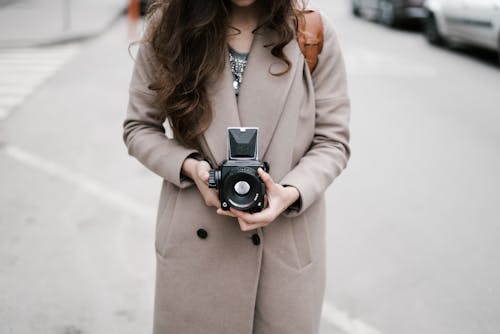 Crop woman with vintage camera on street