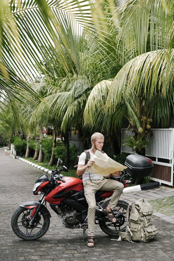 Focused man studying map leaning on motorbike