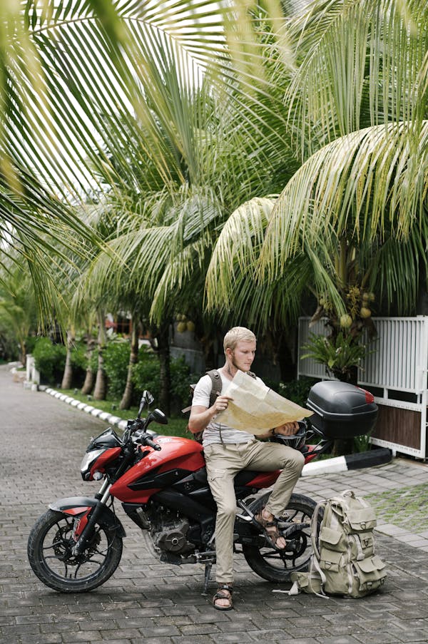 Focused man studying map leaning on motorbike