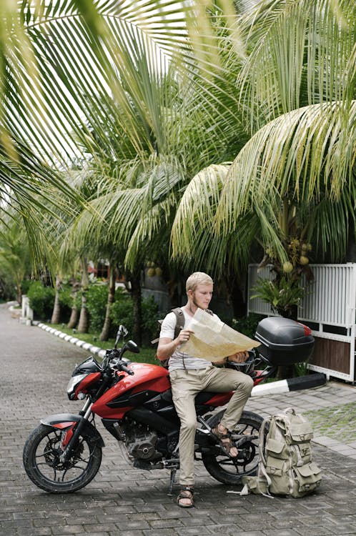 Focused man studying map leaning on motorbike