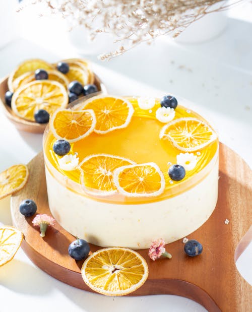 Orange Cheese Cake With Fresh Oranges and Blueberries on Wooden Board