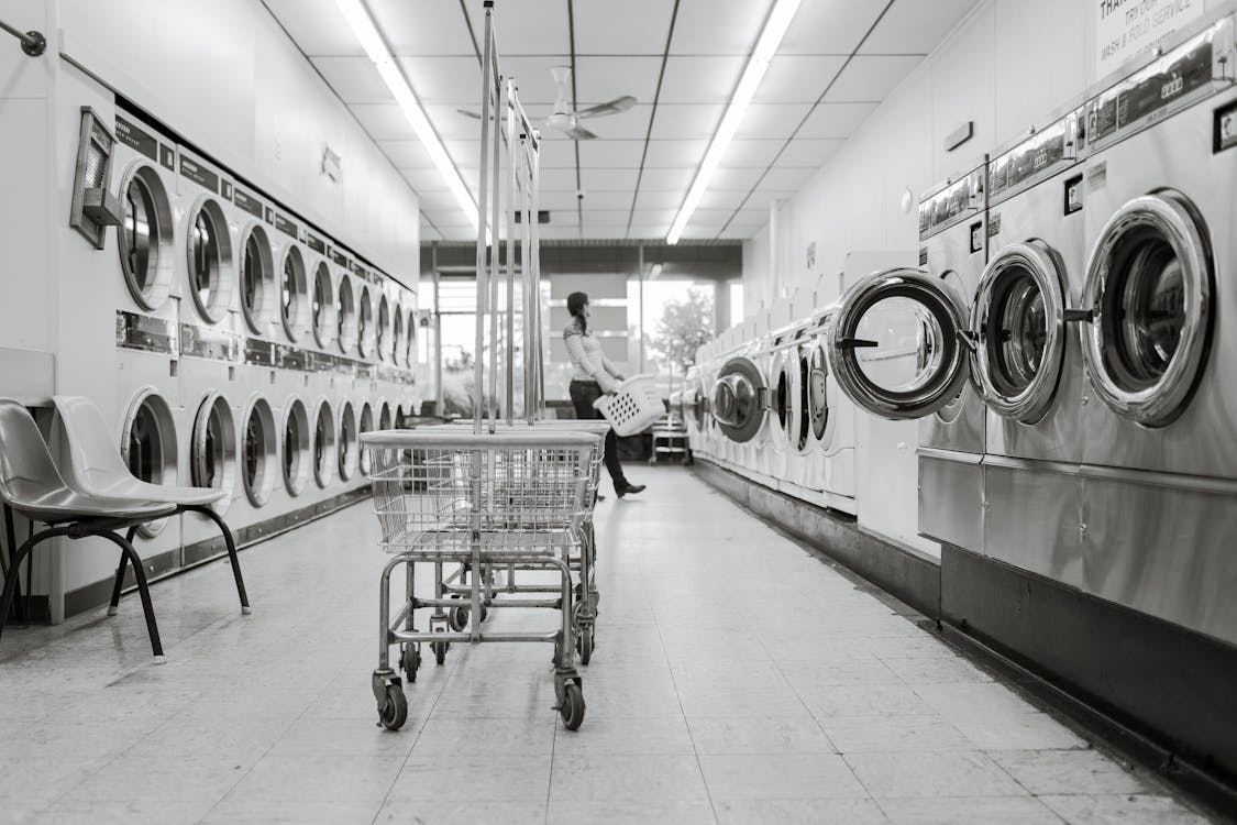 Grayscale Photography of Woman in Laundry Shop
