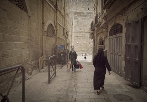 Man in Black Coat Walking on Sidewalk