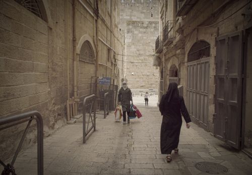 Free People walking through a narrow alleyway in Jerusalem Old City, showcasing historic architecture. Stock Photo
