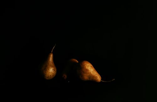 Free Dramatic still life of ripe pears in low lighting against a black background. Stock Photo