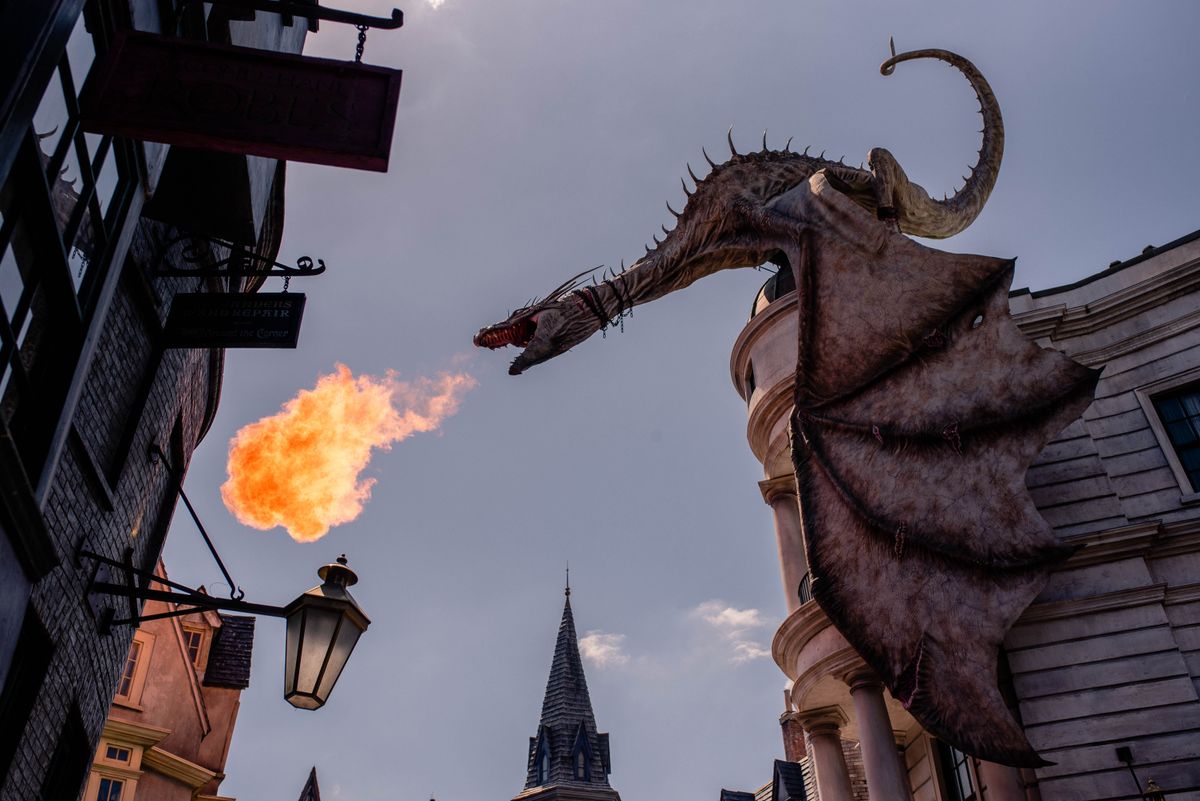 A dragon breathing fire above a night crowd