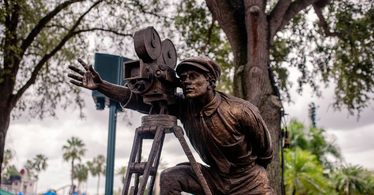 Statue of a filmmaker with vintage camera, located outdoors at a park in Orlando, Florida.