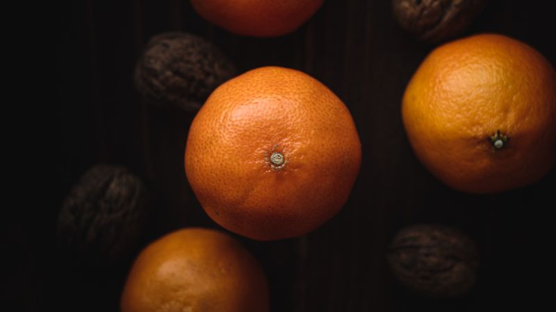 Mandarinen und Walnüsse in der Schale von oben auf einem dunklen Holztisch