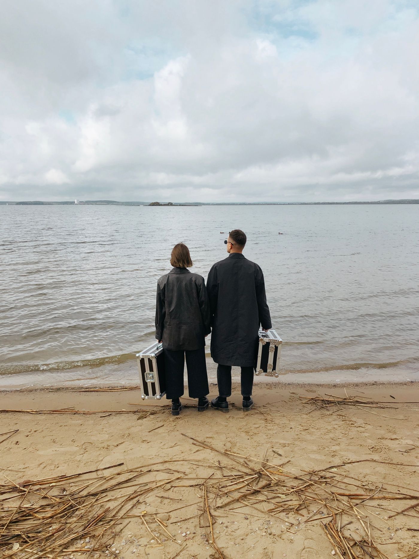 Pareja con maletas frente al mar planeando su próximo viaje
