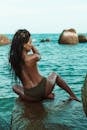 Woman in Green Bikini Sitting on Rock Formation
