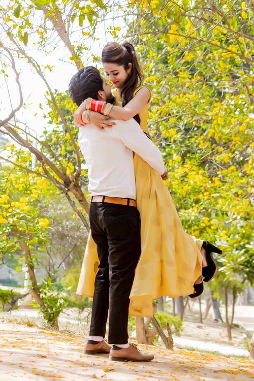 Free A couple in love embraces in a sunlit park with blooming trees, symbolizing romance and happiness. Stock Photo