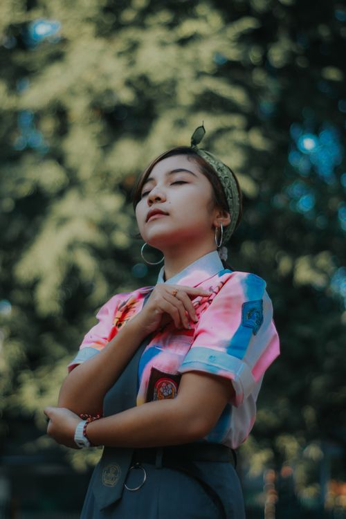 Free Woman enjoying a peaceful moment outdoors with eyes closed, surrounded by nature. Stock Photo