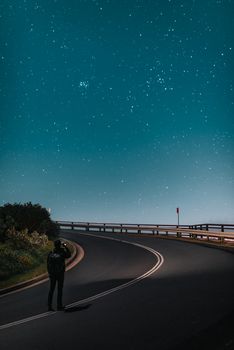 一位孤独的旅行者在拜伦湾一条安静的道路上，凝视着令人惊叹的星空