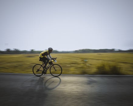 A cyclist in motion on a rural road against a scenic countryside backdrop.