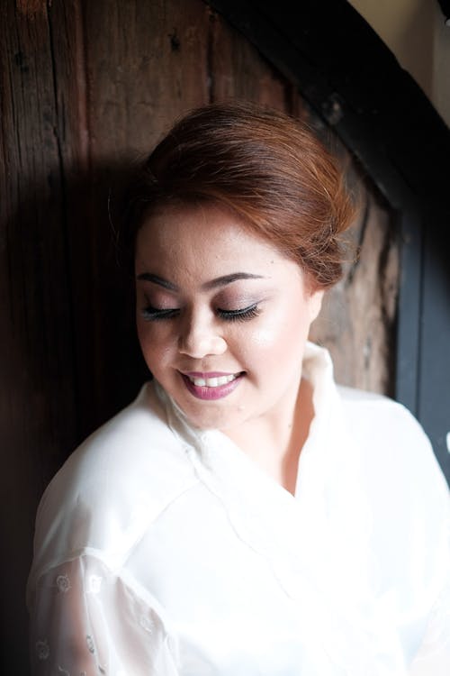 Cheerful young Asian lady resting near wooden wall at home