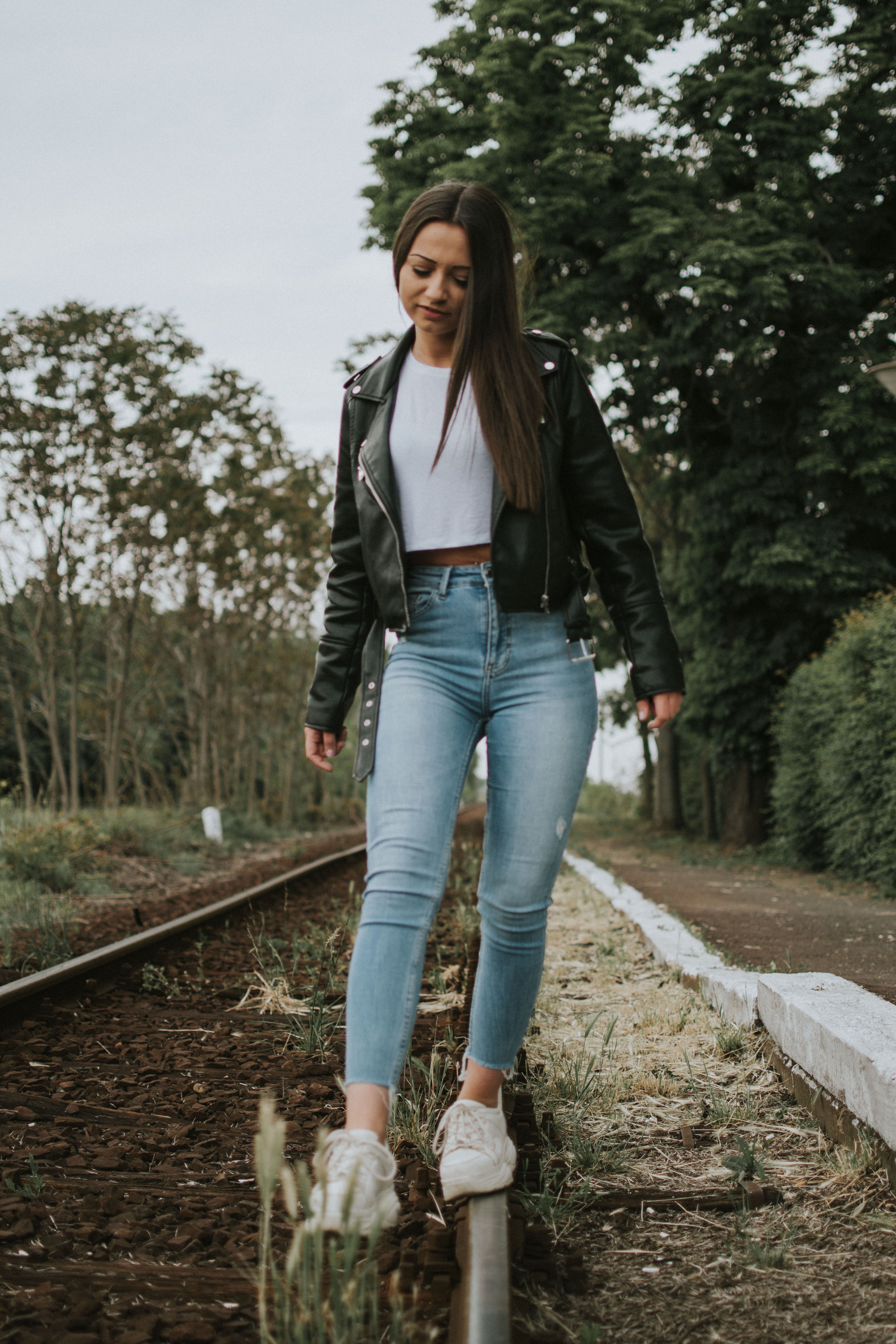 Woman in Black Leather Jacket Walking on a Train Track · Free Stock Photo