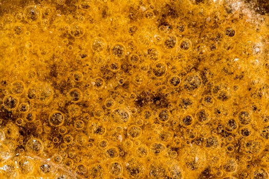 Detailed macro image of golden bubbles and foam creating a textured pattern.
