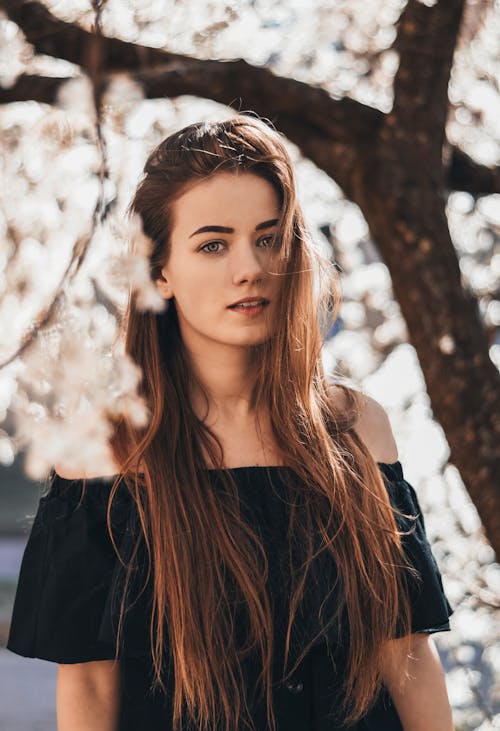 Free Serious woman under blooming tree Stock Photo