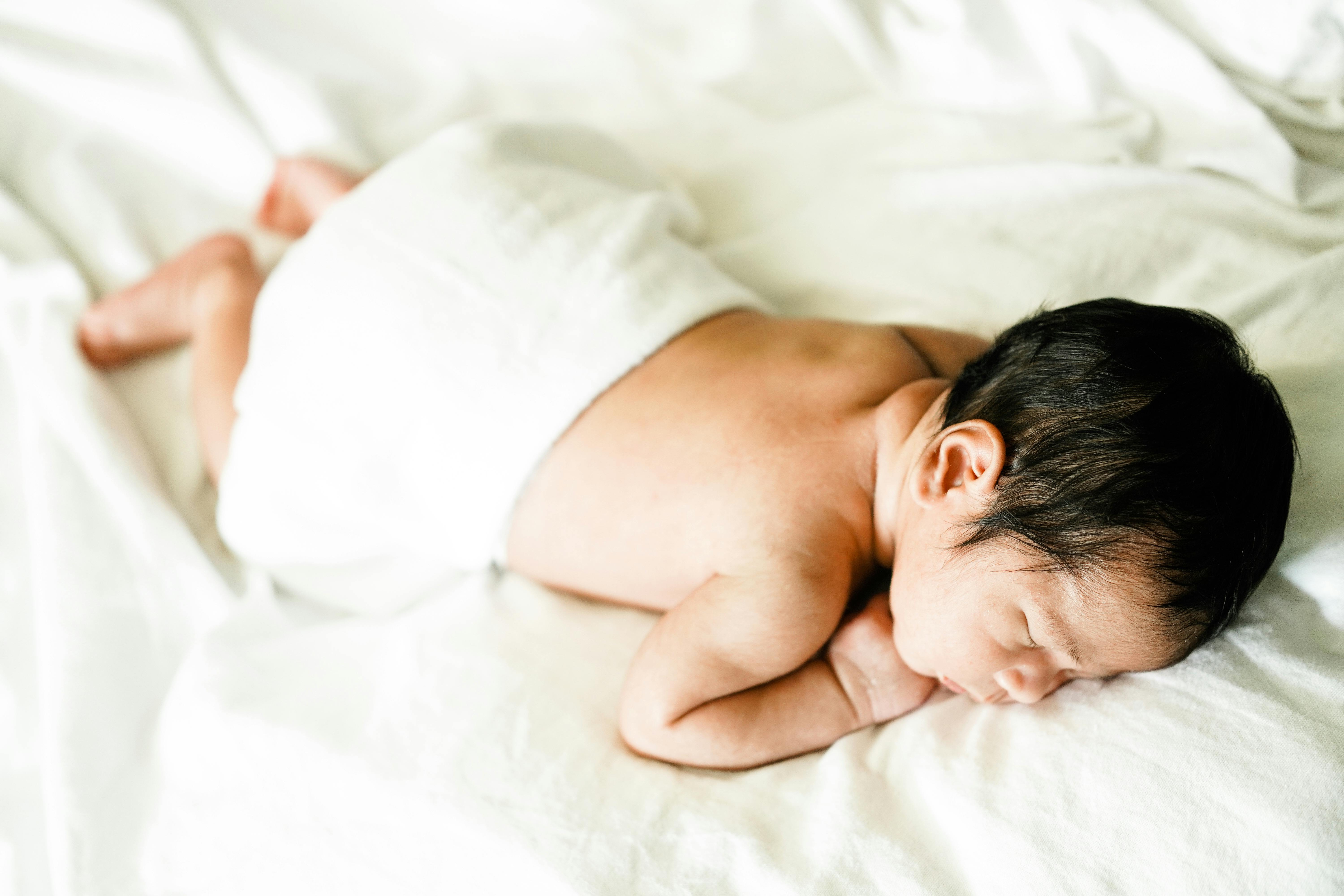 Baby Lying on White Bed · Free Stock Photo