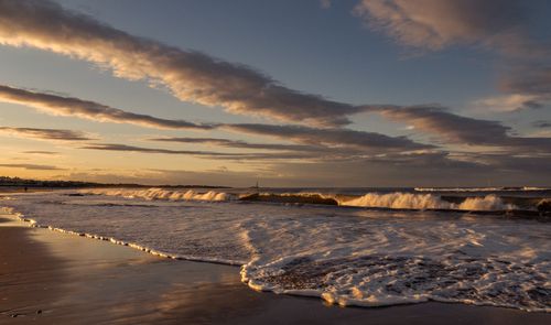 Free Picturesque view of sea waves running on sandy shore under cloudy sundown sky in evening Stock Photo