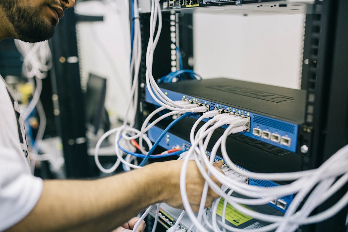 IT technician carefully disconnects cables from a server rack in preparation for relocation.