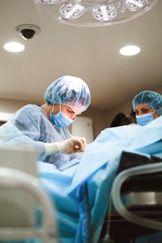 Team of medical professionals performing surgery while wearing protective equipment in a hospital setting.