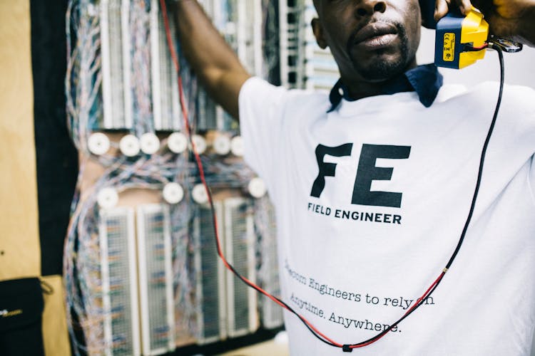 Crop Focused Black Engineer With Handset Checking Connection