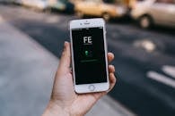 城市环境中，一个人手持智能手机，屏幕上显示着应用程序的特写