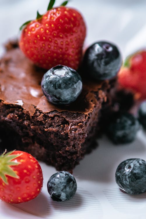 High angle of tasty chocolate cake decorated with strawberries and blueberries on plate