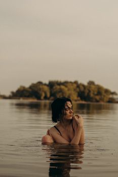 日落时分，一名头发湿漉漉的女子在平静的湖中享受着宁静