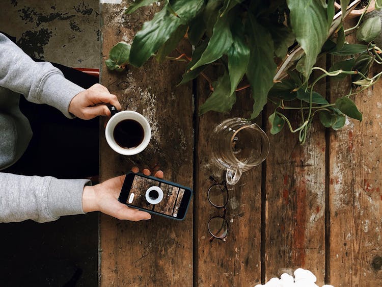 Person Holding A Cup Of Coffee And  Smart Phone