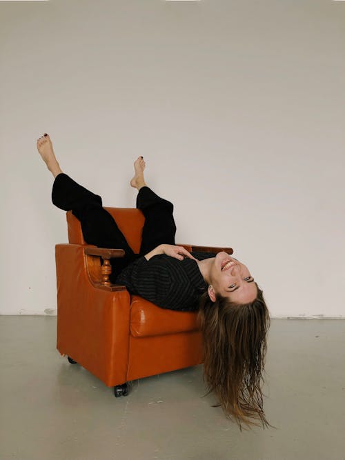Free Woman in Sitting Upside Down in Armchair Stock Photo